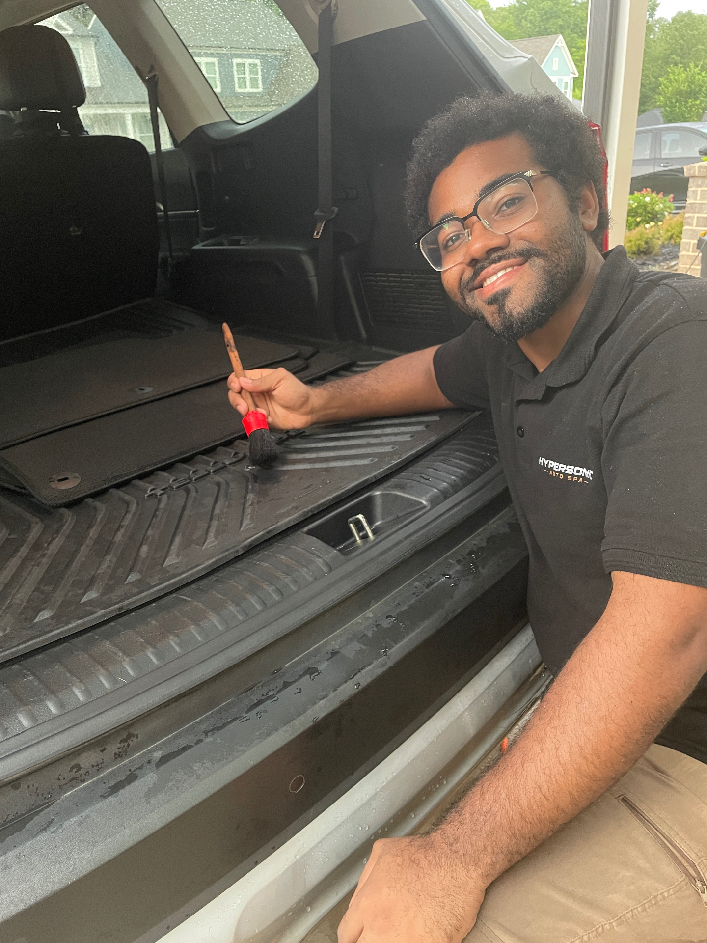 Joshua Johnson detailing an SUV cargo area with a detail brush