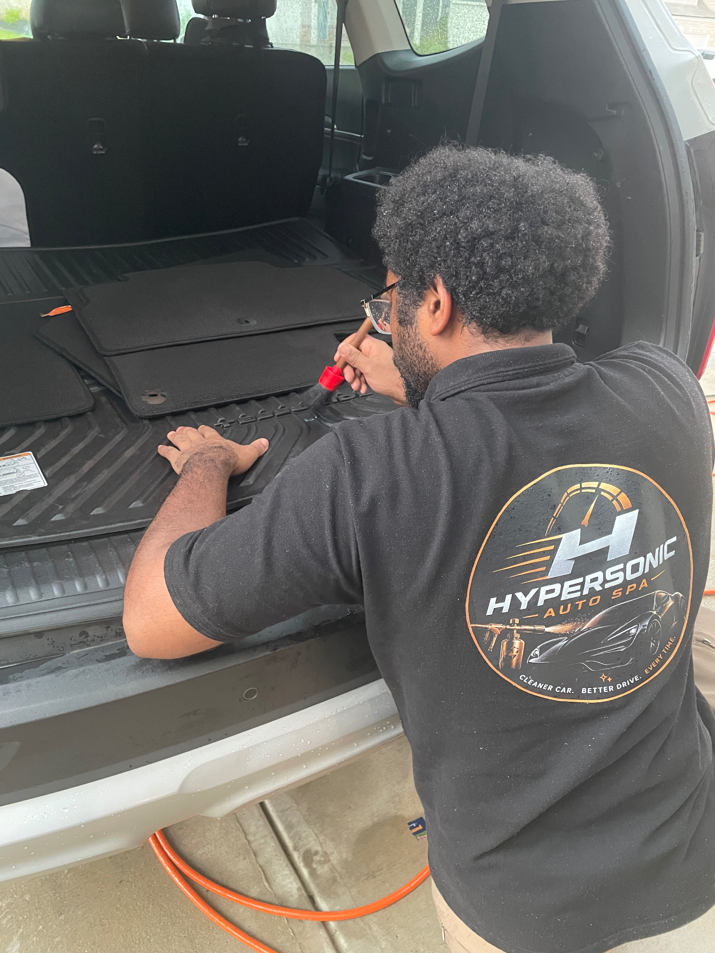 Hypersonic Auto Spa logo on detailer's polo while cleaning cargo area